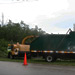 Arborcare garbage truck receiving debris from the wood chipper